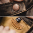 Close-up of a leather product with a brand label and a tag on fabric.